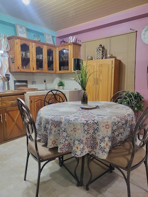 Un comedor con una mesa redonda cubierta por un mantel estampado, rodeado de sillas.