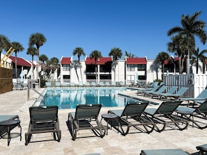 Uima-allasalue, jossa on aurinkotuoleja ja kirkkaan sininen taivas.