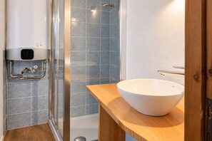 Ein modernes Badezimmer mit Duschkabine aus Glas, einem weißen Waschbecken und einer eingebauten Heizung.