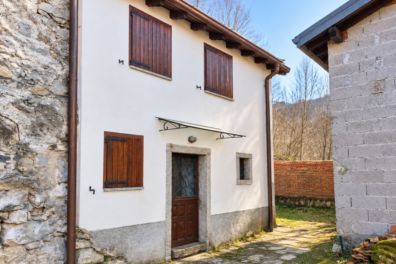 A two-story building with a stone facade, a wooden door, and a small window with a metal frame.