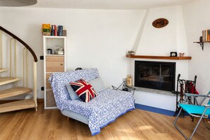 Ein gemütliches Wohnzimmer mit einer Couch, einem Kamin, einem Bücherregal und einer Treppe.