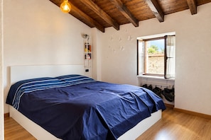 Ein Schlafzimmer mit Bett, Holzboden, einem Fenster mit Blick und einem Schuhregal.