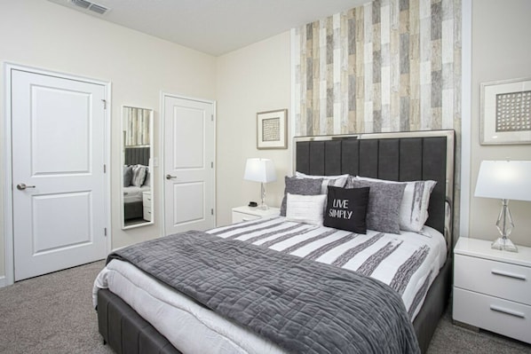 A bedroom with a bed, a nightstand, a mirror, and a door. - Storey Lake 4BR | Pool & Mickey-themed room (Kissimmee)