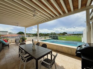A covered outdoor area with a pool, seating, and a view of a sports field. - Breeze & Lake 4BR House in Puntarena (Río Hato)