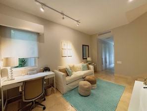A modern living room with a sofa, a desk, and a window. There is a mirror on the wall and a door leading to another room. - Breeze & Lake 4BR House in Puntarena (Río Hato)