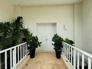 A hallway with a white door, potted plants, and a white railing. - Breeze & Lake 4BR House in Puntarena (Río Hato)
