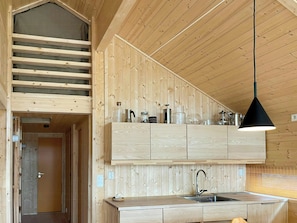 A modern kitchen with wooden cabinetry, a built-in sink, and a hanging pendant light.