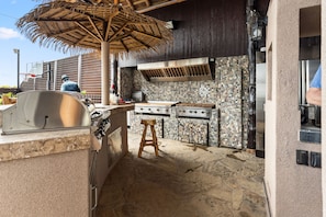 An outdoor kitchen with a grill, a stove, and a dining area with a table and chairs. - The Naughty Flamingo Studio Camper (Bay City)