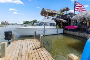 A dock with a boat, a thatched-roof structure, and an American flag. - The Naughty Flamingo Studio Camper (Bay City)