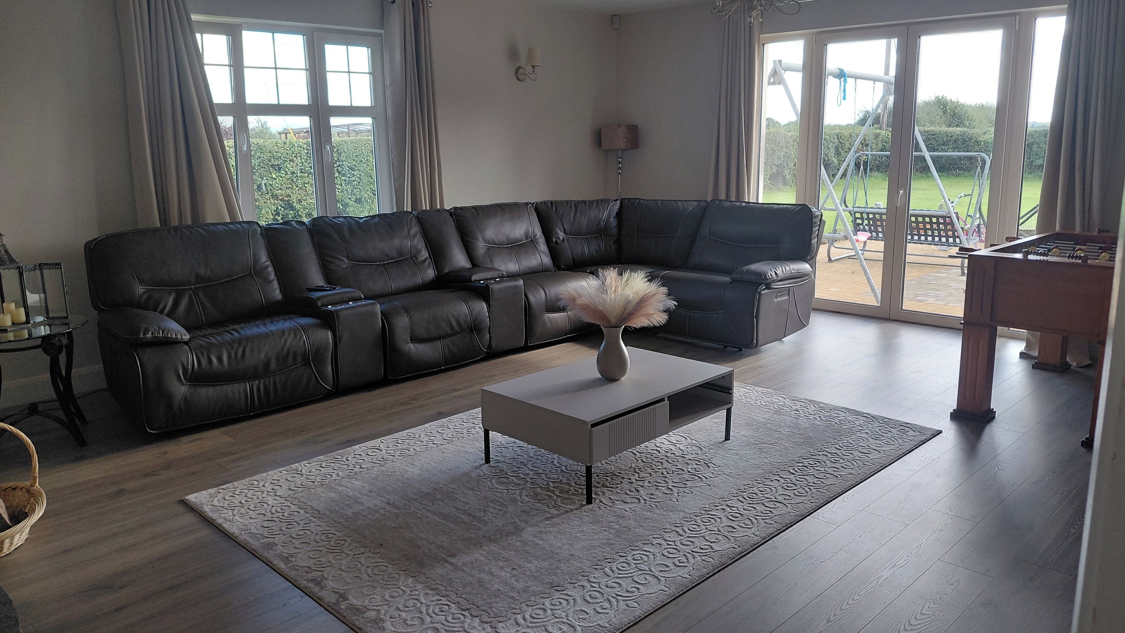 A living room with a sectional sofa, a coffee table, and a view of the outdoors.