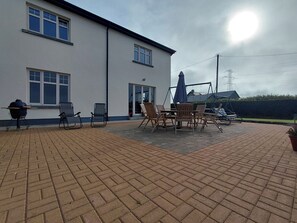 A patio area with a barbecue grill, outdoor seating, and a swing set. - Limerick Luxe Villa Retreat (Limerick)