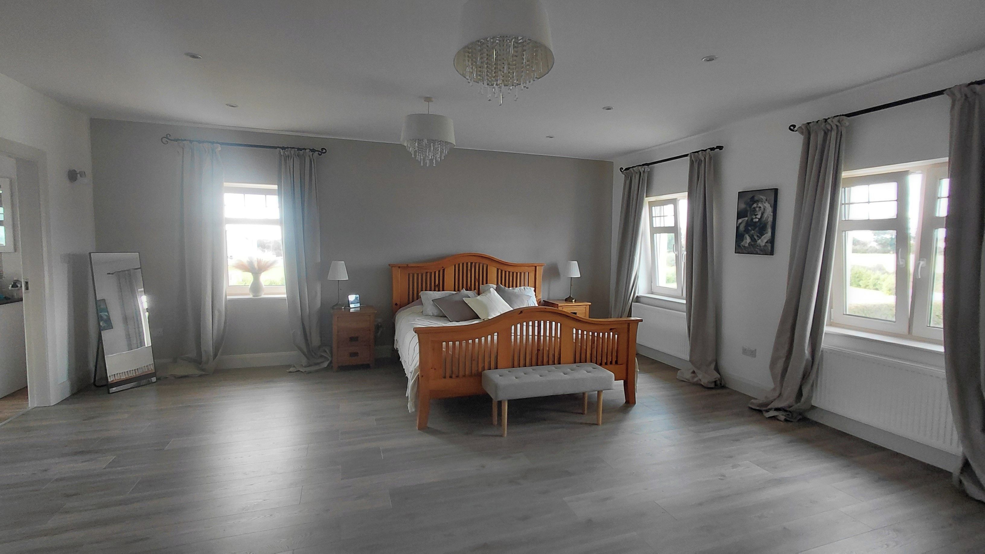 A bedroom with a wooden bed, bedside tables, a mirror, and a chandelier.