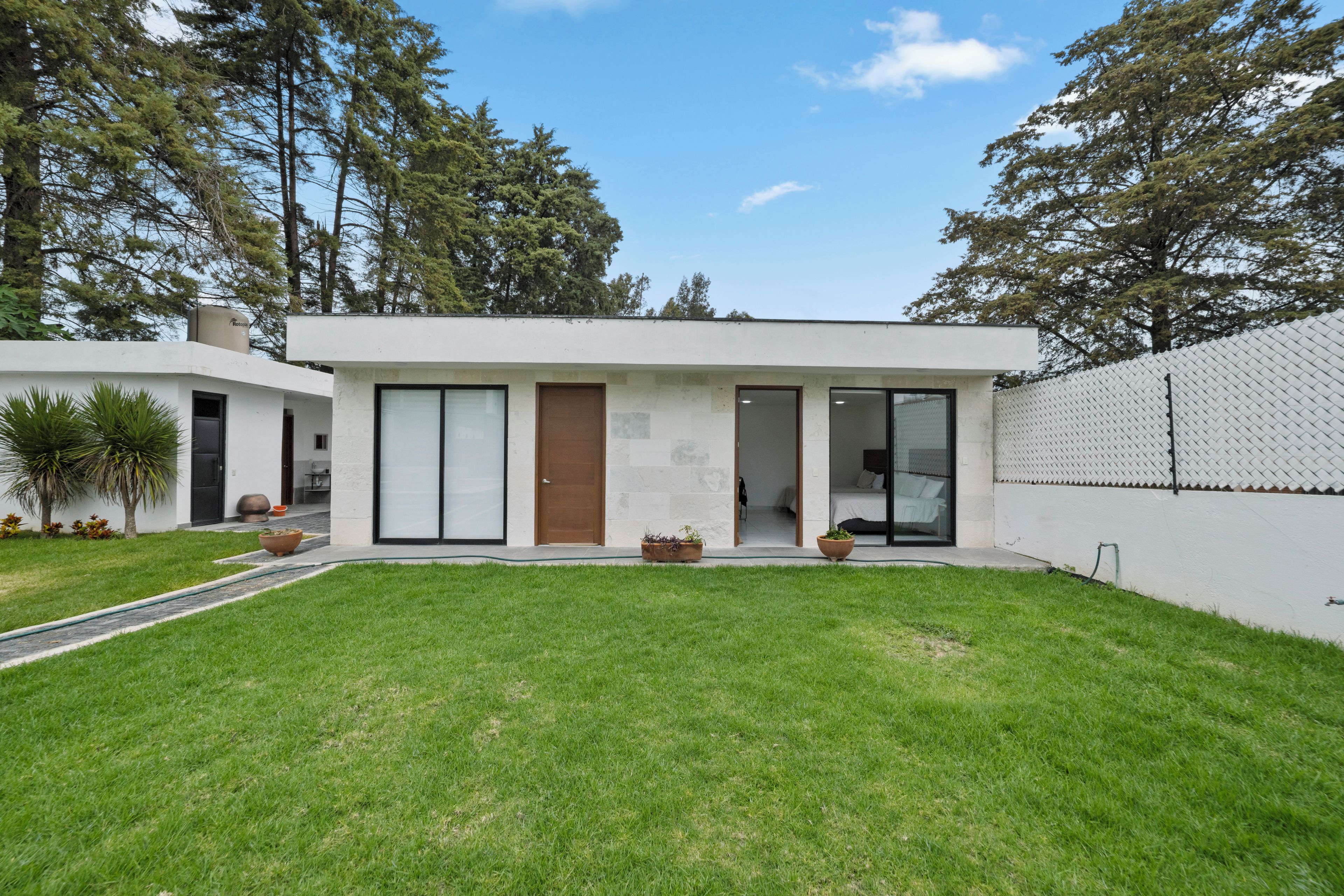 A modern two-story house with a flat roof, large sliding glass doors, and a small front porch.