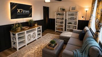 A living room with a sectional sofa, a white entertainment unit, a ceiling fan, and a wall-mounted TV.