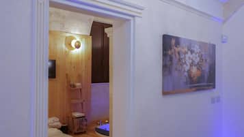 A room with a wooden door, a painting on the wall, and a small bathroom with a toilet and sink.
