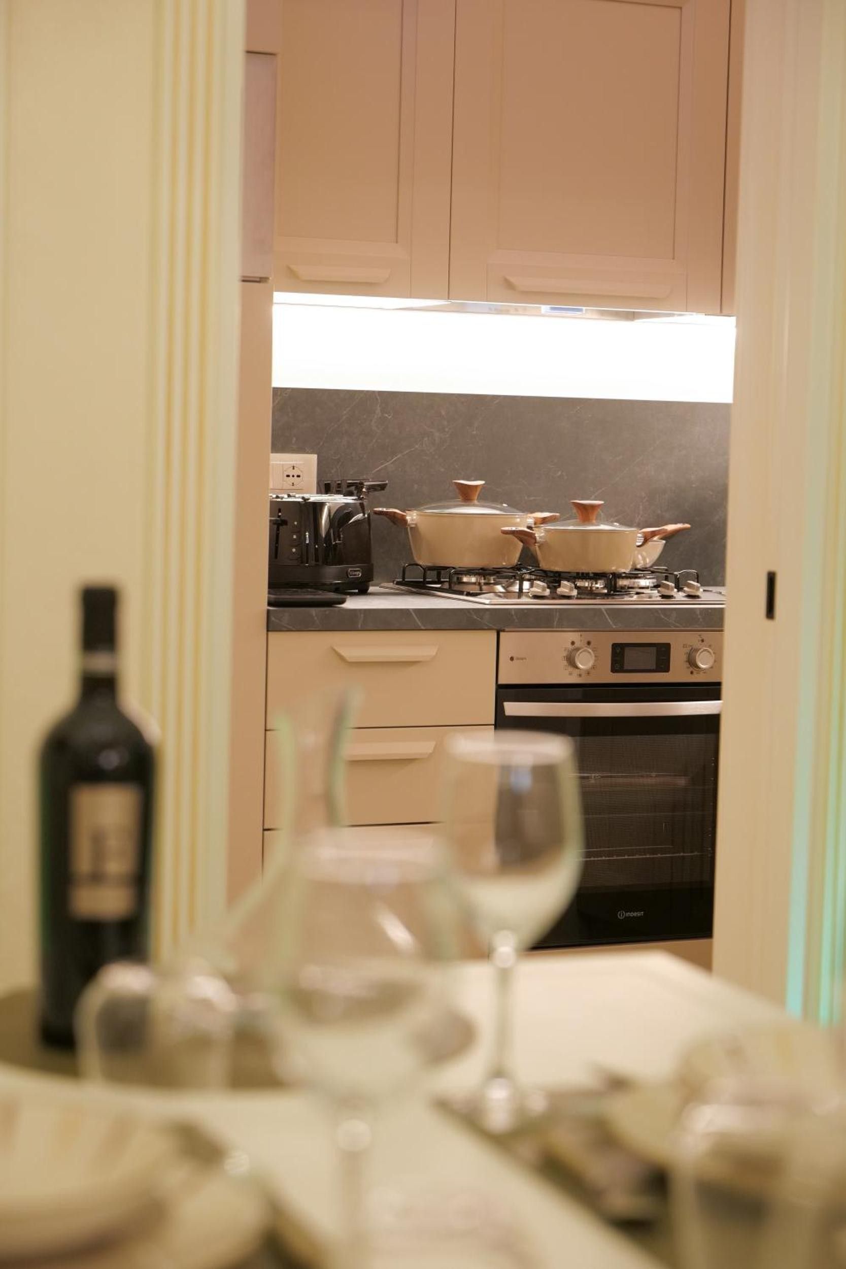 A kitchen with cabinets, a stove, and a wine bottle.