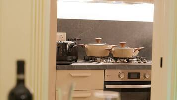 A kitchen with cabinets, a stove, and a wine bottle.
