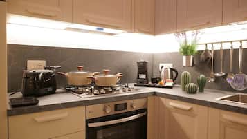 Cocina moderna con estufa a gas, horno y cafetera.