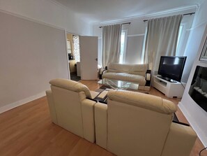 Una sala de estar con sofá, mesa de centro, televisor y chimenea.