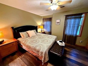 A hotel room with a bed, bedside table, lamp, and a ceiling fan. - The Burrow at Silver Creek | Ski Access, Hot Tub (Snowshoe)