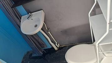 A bathroom with a white sink, a toilet, and a shower area.