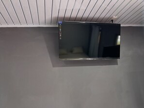 Un televisor de pantalla plana montado en la pared, con un panel de control a la izquierda.