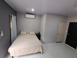 A bedroom with a bed, a nightstand, an air conditioning unit, a door, and a tiled floor. - Premium Home  (La Paz Oeste)