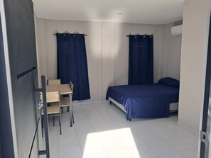 Quarto pequeno e limpo, com uma cama, escrivaninha e uma cadeira.