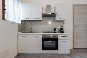 Eine kompakte Küche mit weißen Schränken, einem Gasherd, einem Backofen und einem Spülbecken.