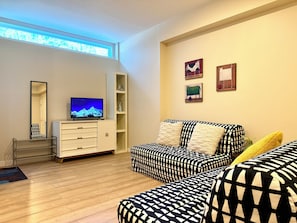 A living room with a sofa, a television, a mirror, and a window. - Cedar Grove Residence (Surrey)