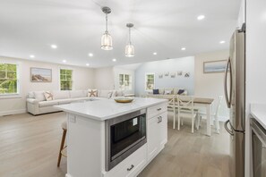 Una cocina moderna con una isla central, muebles blancos y electrodomésticos de acero inoxidable.