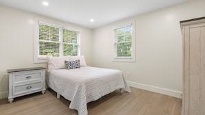 Un dormitorio con cama, mesita de noche y ventana con persianas.