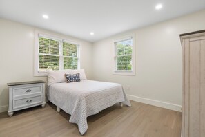 Ein Schlafzimmer mit einem Bett, einem Nachttisch und einem Fenster mit Jalousien.