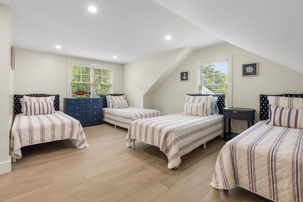 Un dormitorio con tres camas, un aparador y un escritorio.