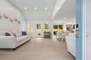 Amplia sala de estar con sofá, mesa de comedor y zona de cocina con refrigerador.