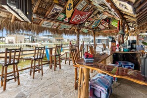 A rustic bar area with wooden furniture and a thatched roof, overlooking a body of water. - The Lady Luck In Water Docked Studio Boat Room (Bay City)