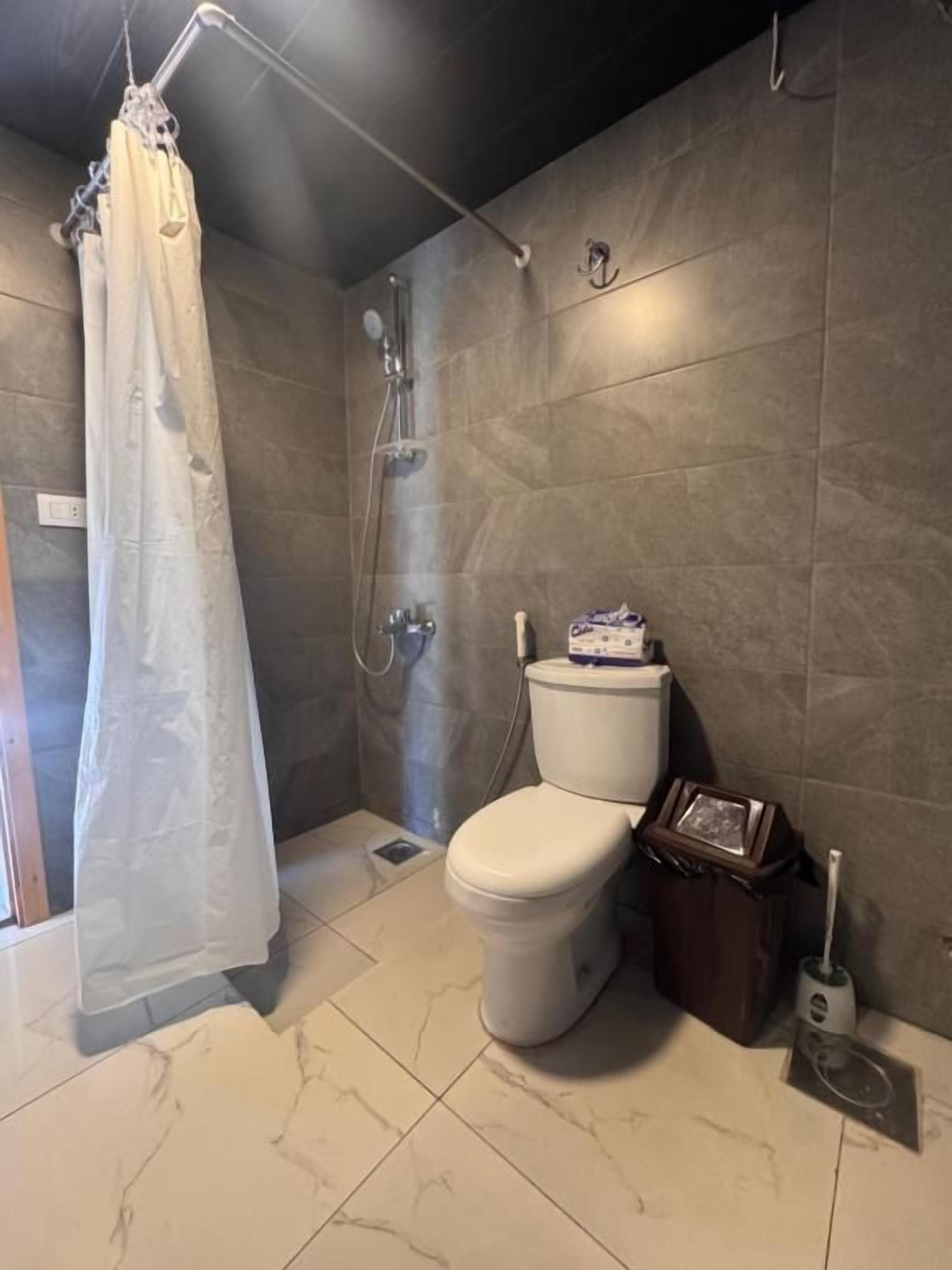 Un baño con ducha, inodoro y toallero.