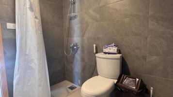 Un baño con ducha, inodoro y toallero.