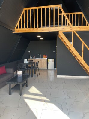 A loft-style living space with a kitchen area, a dining table, and a staircase.