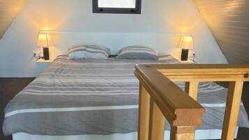 A bedroom with a bed, two bedside lamps, a window, and an air conditioning unit.