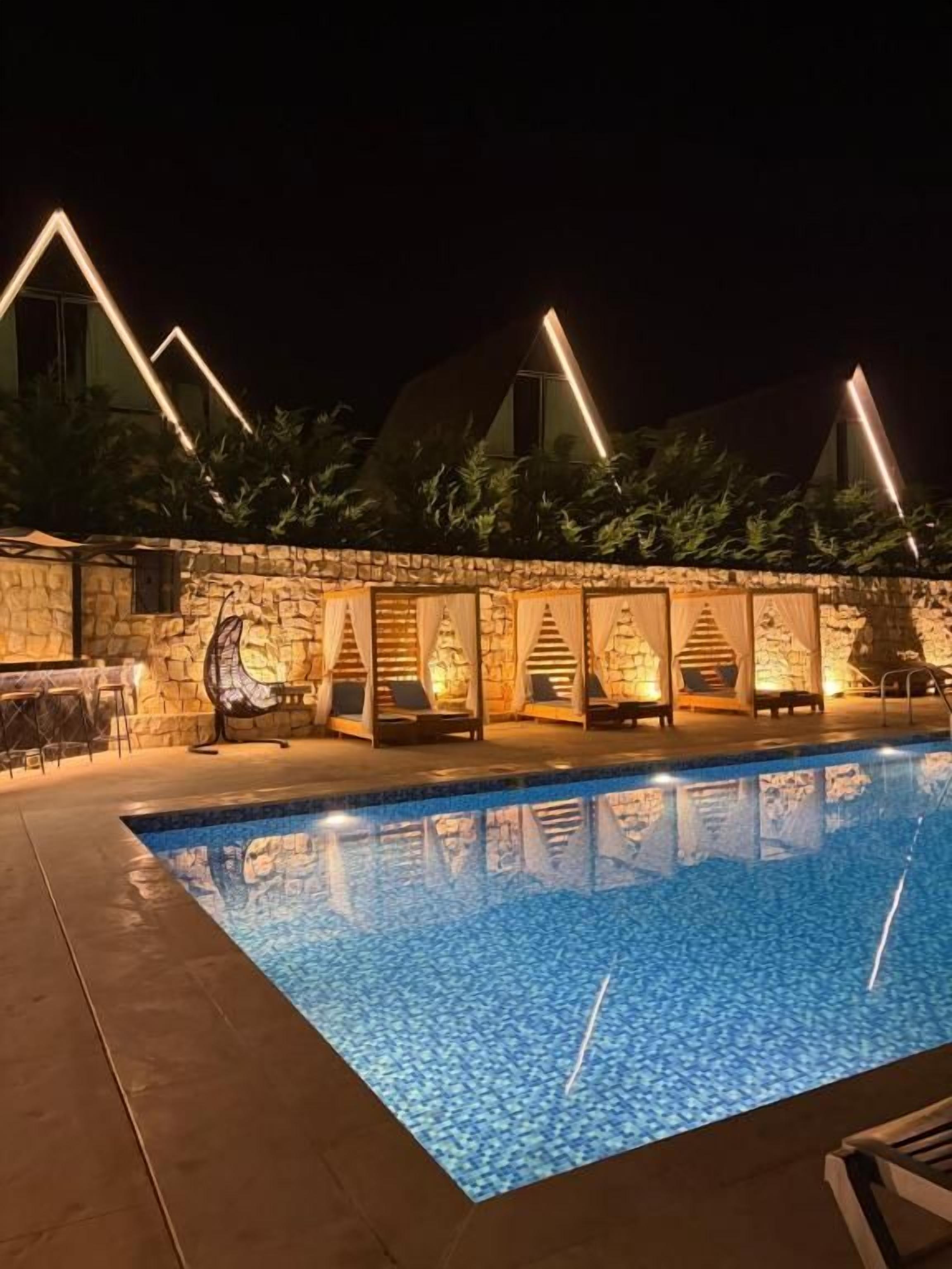 A swimming pool with stone walls and outdoor seating.
