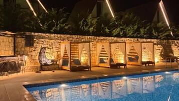 A swimming pool with stone walls and outdoor seating.