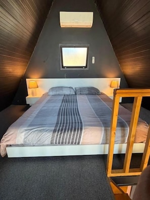 A room with a bed, a window, and a wall-mounted air conditioner.