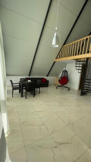 A dining area with a table and chairs, a hanging light fixture, and a staircase leading to an upper level.