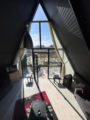 Une pièce confortable avec une grande fenêtre, un canapé, une table et un barbecue.