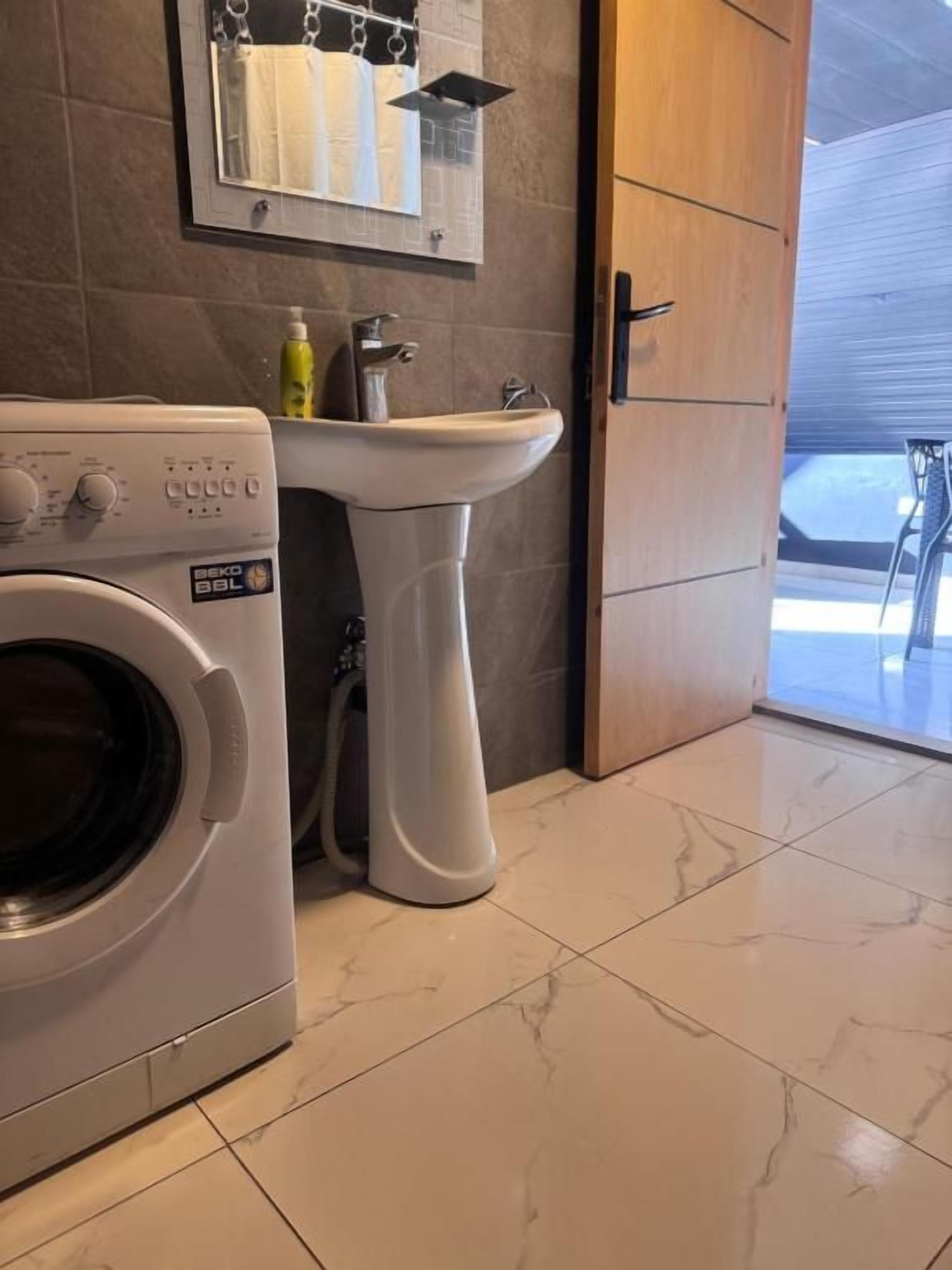 A laundry area with a washing machine and a sink.