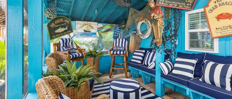 A vibrant, nautical-themed lounge area with wicker furniture, striped cushions, and maritime decor.