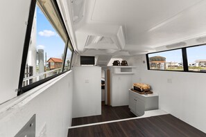 Un intérieur compact avec un couloir étroit, un petit coin salon et une fenêtre donnant sur l’extérieur.