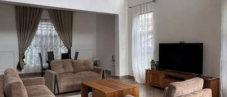 A spacious living room with a large flat-screen TV, comfortable sofas, and a wooden coffee table.