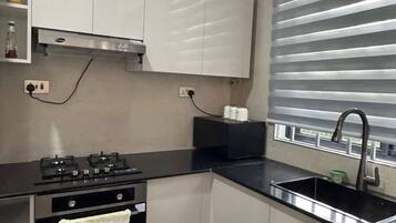 Una cocina moderna con horno integrado, encimera negra y pileta de acero inoxidable.